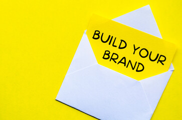 Build Your Brand text on yellow notepad in a white envelope. Branding concept