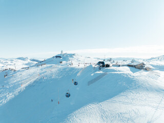 Aerial view of ski resort with gondolas snowy slopes buildings clear sky Winter wonderland scene