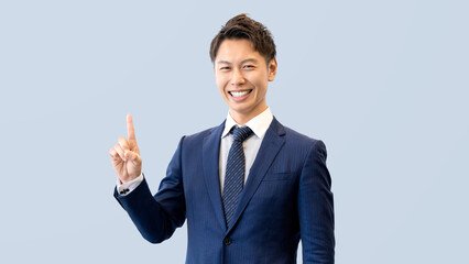 人差し指を立てて案内する笑顔の男性ビジネスマン