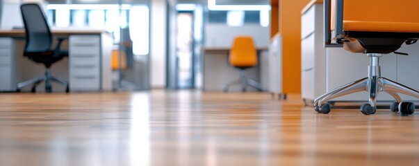 Modern office space featuring sleek wooden floors, orange accents, and stylish chairs, creating a vibrant and inviting work environment.