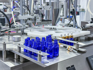 Glass bottles in a conveyor belt on a high quality automatic vertical filling machine. In the...