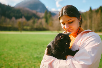 Female hiker with black cat in mountain landscape