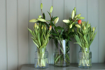 Bouquet of tulips in a glass vase on an olive cabinet. Spring flowers close up photo. Mother's day celebration concept. 