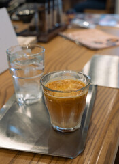 A clear glass cup of dirty coffee latte on a table. It's a coffee consists of cold milk, sometimes a mixture of milk and cream, combined with solid espresso or ristretto.