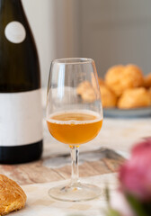 A glass of French apple cider on table with its bottle in background, from region cider called Normandy. It's a beverage made from a blend of apple varieties. 