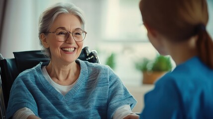 Obraz premium Old lady in glasses sitting in a wheelchair and smiling at her nurse