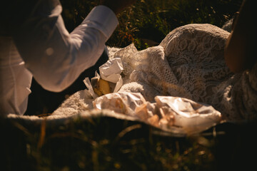 Obraz premium Detail of a picnic at sunset with a bridal dress and champagne