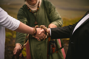 Details of a pagan handfasting ceremony with a weaved ribbon in Iceland