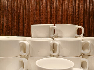 Neatly Stacked White Ceramic Mugs On A Table With A Brown Wooden Background