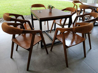 Outdoor Cafe with Wooden Chairs Arranged Around a Brown Square Table on Terrazzo Flooring