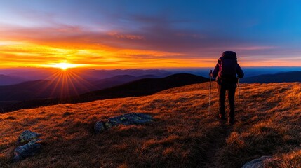 Obraz premium Silhouette of a hiker on a mountain peak with backpack and trekking poles against a scenic landscape
