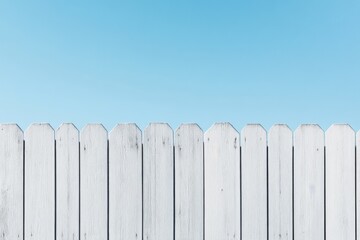 Snowy fence standing tall under a bright blue sky during a serene winter afternoon