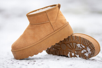 Stylish suede winter boots resting on snowy ground
