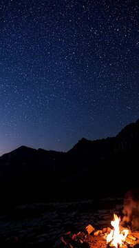 Stars emerging over the mountain, the sky shifting from indigo to midnight blue, as a lone campfire flickers, radiating warmth. Vertical video backgrounds
