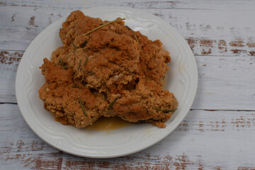 Cooked seitan on white  plate, wooden table