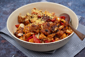 Fried seitan with cabbage and pepper in light bowl on textured table,