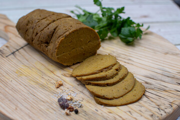 Vegan seitan gluten meat, rolled, steamed and sliced, wooden board.