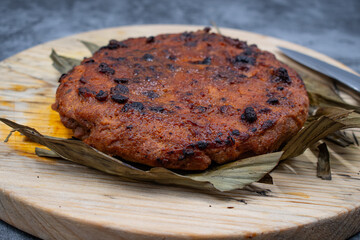 Vegan steak roasted in air fryer. Made of wheat gluten and tofu- seitan. Sliced, on wooden board, on banana leaf.