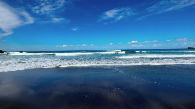 Waves on the coast of the Atlantic ocean on a sunny winter day and a black sand beach in Tenerife