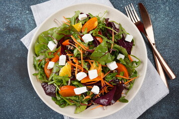 Orange Salad of lettuce mix, toasted almonds, dried cranberries, red onion and feta cheese in white bowl