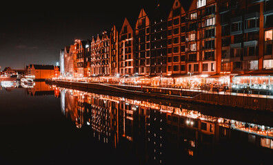 Fototapeta premium A stunning nighttime view of traditional half-timbered buildings reflecting in the calm waters of a river