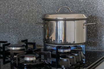 Close up of a stainless steel pan on a gas stove with a burning burner