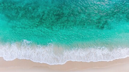 Obraz premium Aerial View of Crystal Clear Turquoise Ocean Waves Gently Rolling onto Golden Sandy Beach Under Bright Summer Sunlight in Tropical Paradise