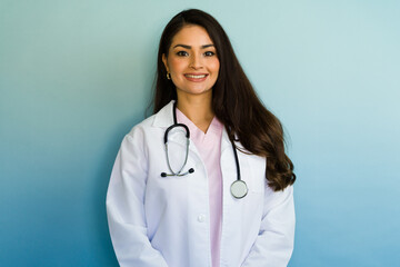 Portrait of smiling hispanic female doctor wearing white coat and stethoscope