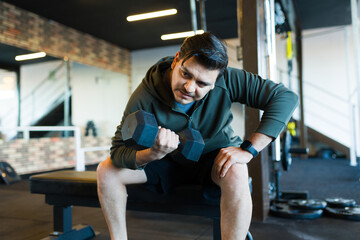 Latin man straining during weightlifting, building strength at fitness center