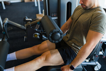 Athletic man intensively working out on a leg press machine in a gym, showcasing strength and...