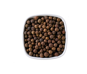 allspice or Jamaican pepper in a ceramic bowl isolated on white background, top view.