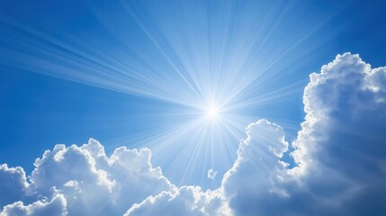 Bright sunbeams through clouds in a clear blue sky