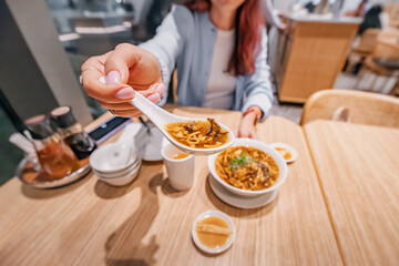 Customer enjoying traditional chinese hot and sour soup in a modern restaurant