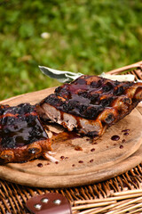 Grilled pork ribs on a wooden board. Barbecue. Picnic. Grilled meat with a sweet and sour sauce on a wooden board. 