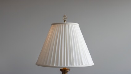 Minimalist lampshade with intricate pleats elegantly illuminated against a simple gray backdrop showcasing sharp details and textures.