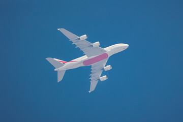 A large commercial airplane in flight against a bright blue sky, representing air travel,...