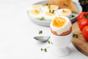 Soft boiled egg on white tiled table, closeup. Space for text