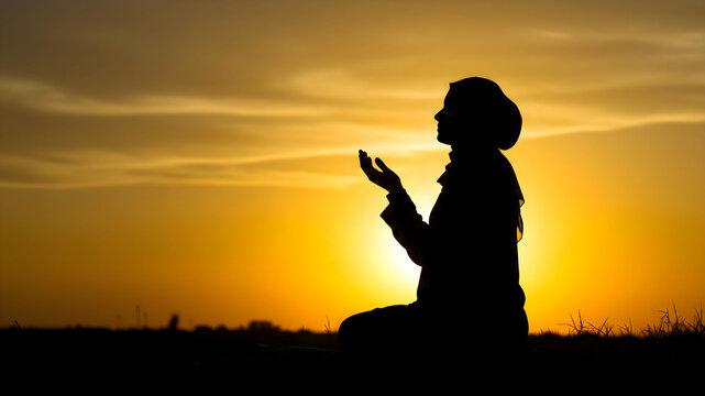 Woman in prayer silhouetted against a glowing sunset, featuring raised hands in worship, showcasing spirituality, devotion and tranquil connection