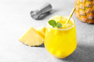 Tasty pineapple cocktail with mint in glass on gray table, closeup