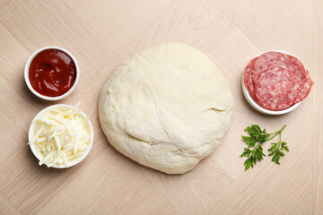 Making calzone pizza. Dough and ingredients on wooden table, flat lay