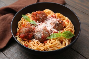 Delicious pasta with meatballs and cheese in bowl on wooden table, closeup