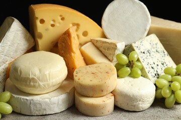 Different types of cheese and grapes on grey table, closeup