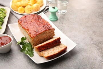 Delicious baked turkey meatloaf with vegetables served on grey table, closeup. Space for text
