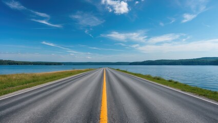 Fototapeta premium Asphalt Road Stretching Along Serene Lake Under Bright Blue Sky with Lush Greenery on the Sides