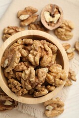 Peeled walnuts in bowl on light table, top view