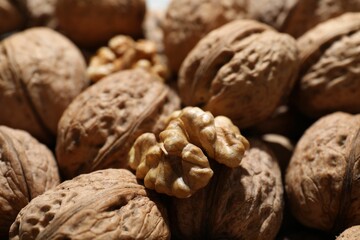 Fresh walnuts in shells and shelled one as background, closeup