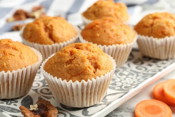 Tasty carrot muffins and cut vegetable on white marble table, closeup