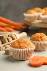 Tasty carrot muffins, sugar and fresh vegetables on light grey table, closeup