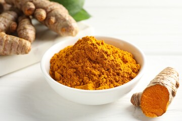 Aromatic turmeric powder and fresh roots on white wooden table, closeup