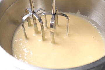 Making dough in bowl with hand mixer, closeup